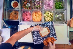 A man assembles a fried chicken bao bun