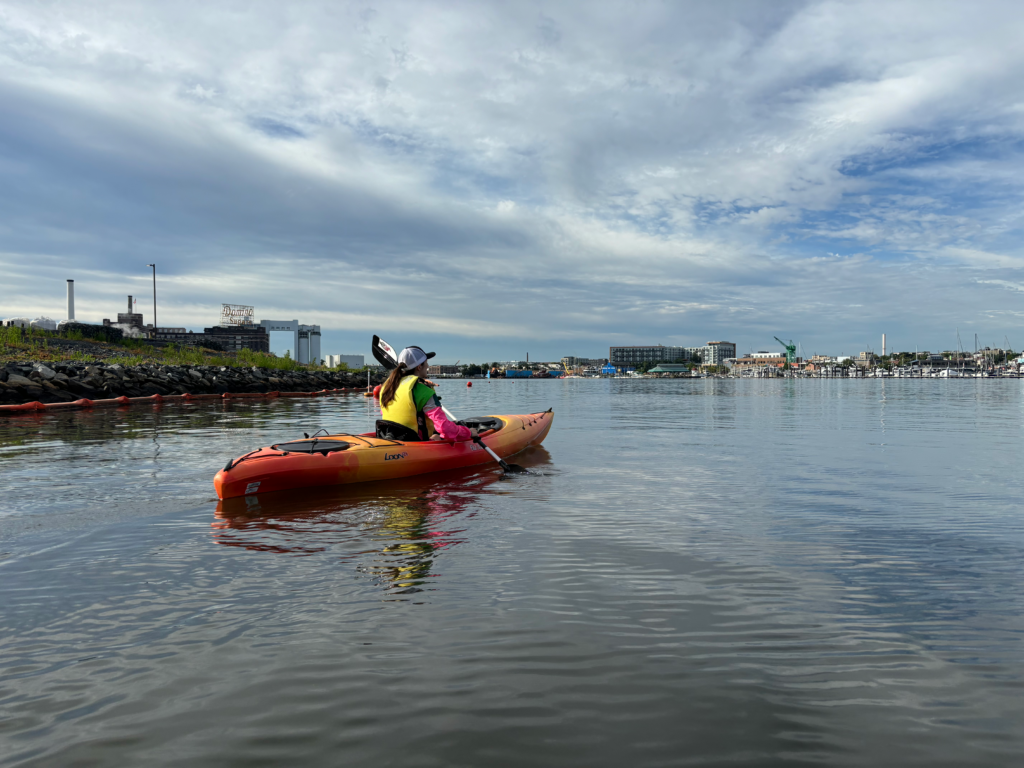 A kayaker cruises on the Patapsco River near the Domino Sugar Sign