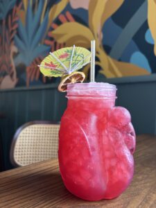 A bright pink cocktail with an umbrella in it
