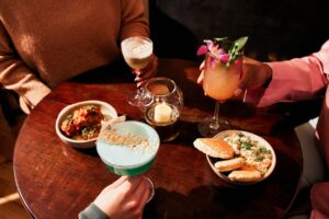 hands holding drinks with plates on a table