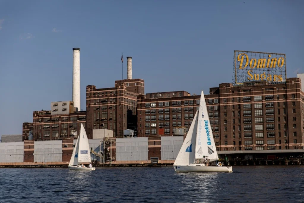 Two sailboats on the harbor in front of Domino Sugars factory