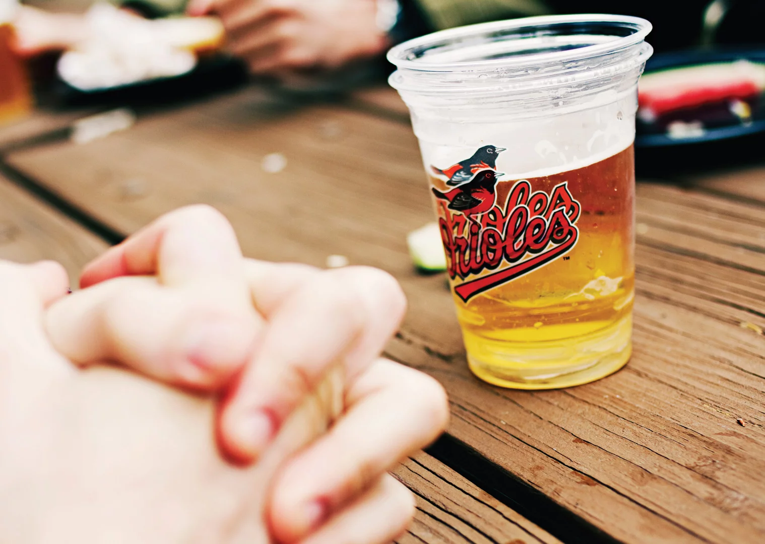 Hands clasped at a table with beer at Camden Yards.