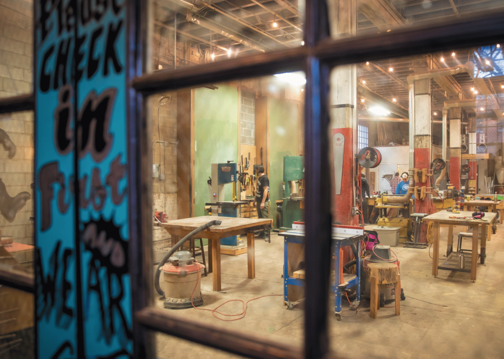 Through a window at Station North Tool Library, a bright and rustic workshop is visible.