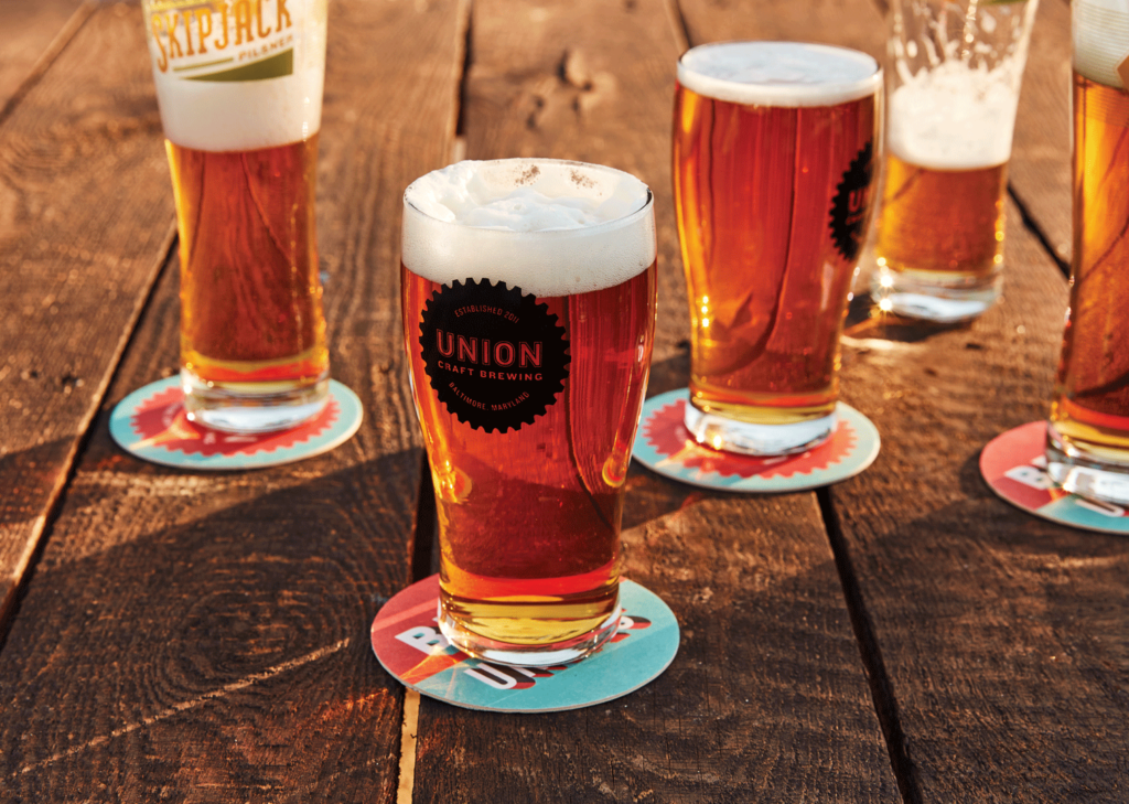 Several pints of Union Craft beer sit on branded coasters on a wooden table.