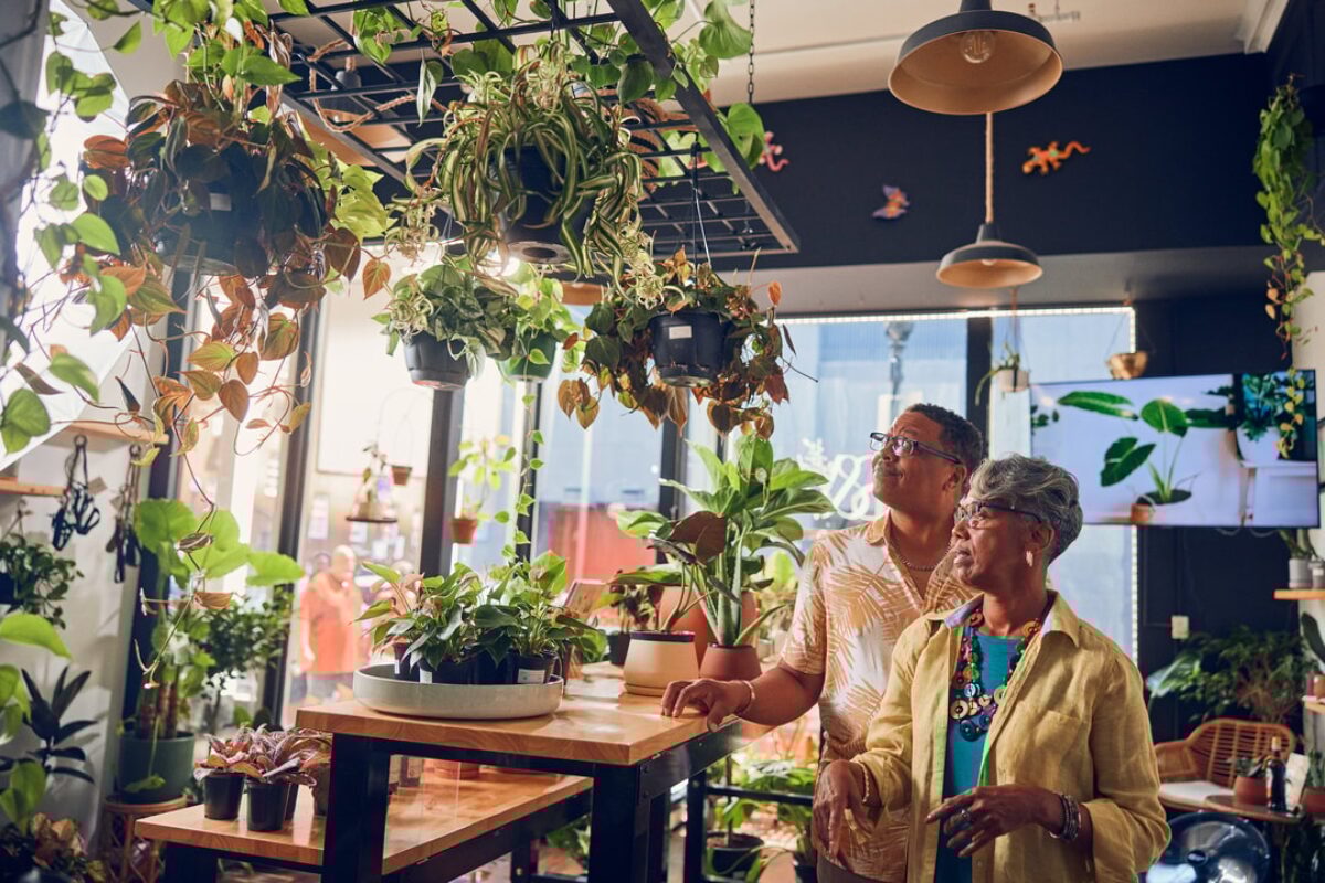 An elderly Black couple walks through a plant store