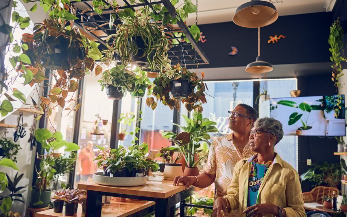 An elderly Black couple walks through a plant store