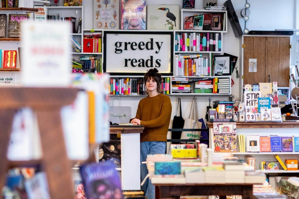 Greedy Reads Bookstore owner standing among books