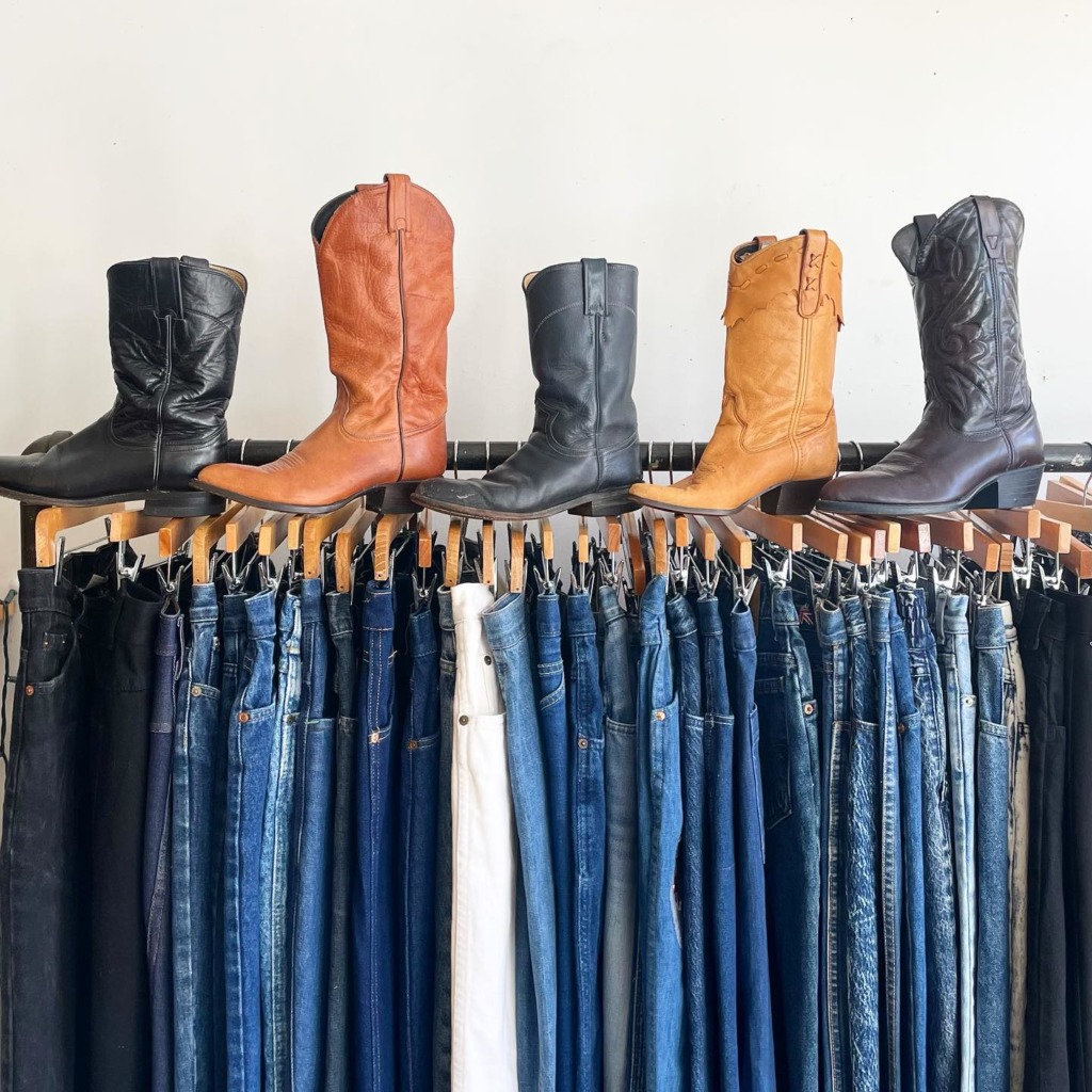A rack of jeans with cowboy boots on top