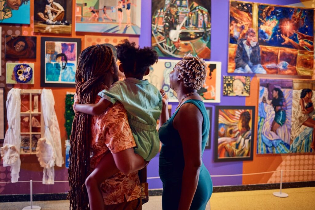 A Black family admires a colorful art exhibit