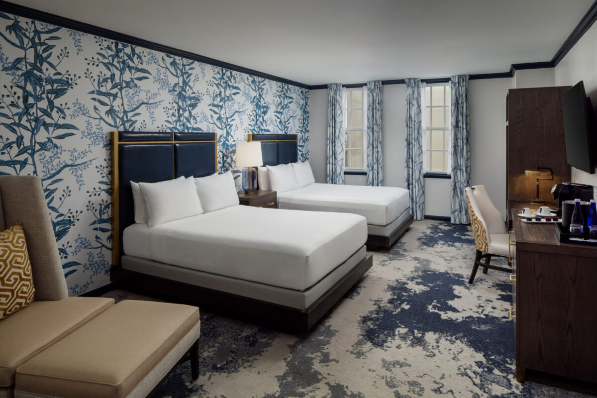 Experience comfort and style in this spacious guest room featuring two queen-sized beds at The William Fell Baltimore, Tapestry Collection by Hilton. Designed with a blend of modern elegance and historic character, the room offers warm, inviting décor, rich textures, and thoughtful details throughout. Each bed is dressed in crisp, high-quality linens and accented with tasteful pillows, providing a restful retreat for families or groups. Additional features include a well-lit work area, cozy seating, and a sleek, contemporary bathroom—all set against the backdrop of the hotel's distinctive Baltimore charm.