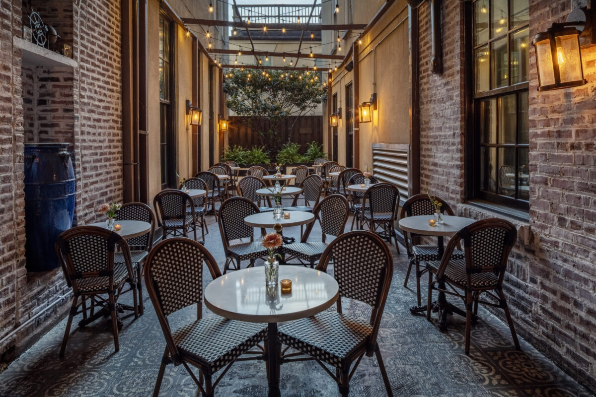 As the sun sets over Baltimore, the private courtyard at The William Fell Baltimore, Tapestry Collection by Hilton transforms into a serene oasis. Soft golden light bathes the charming space, highlighting the lush greenery and inviting seating areas. The tranquil ambiance offers a peaceful retreat, perfect for unwinding after a day of exploring the city or enjoying a quiet moment outdoors. Whether you're relaxing with a drink or simply soaking in the beauty of the moment, this hidden gem offers an unforgettable escape in the heart of Baltimore.