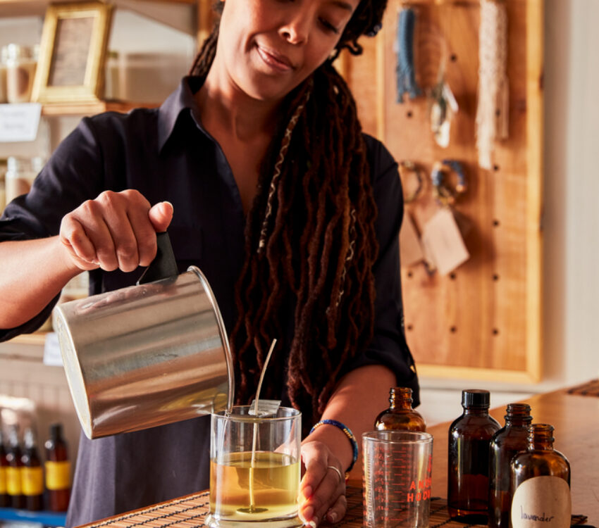 a woman pours wax into a glass container