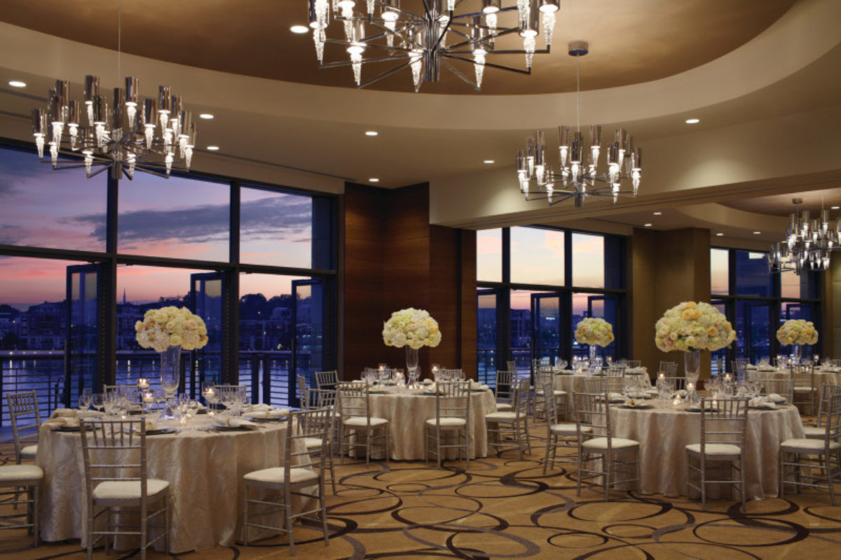 Ballroom decorated with white flowers with the sunset seen through the window.