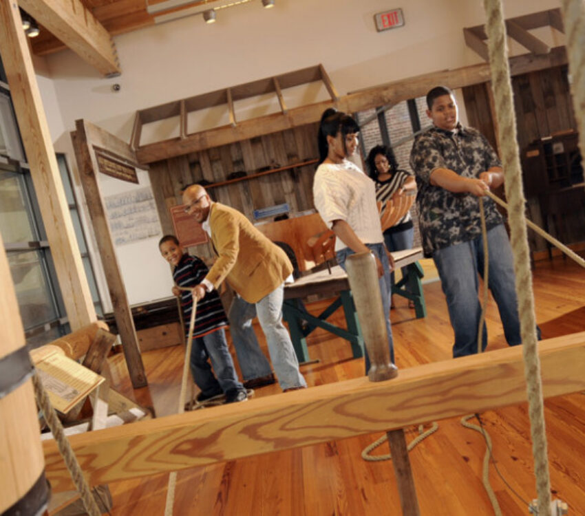 People interacting with an exhibit with ropes and barrels