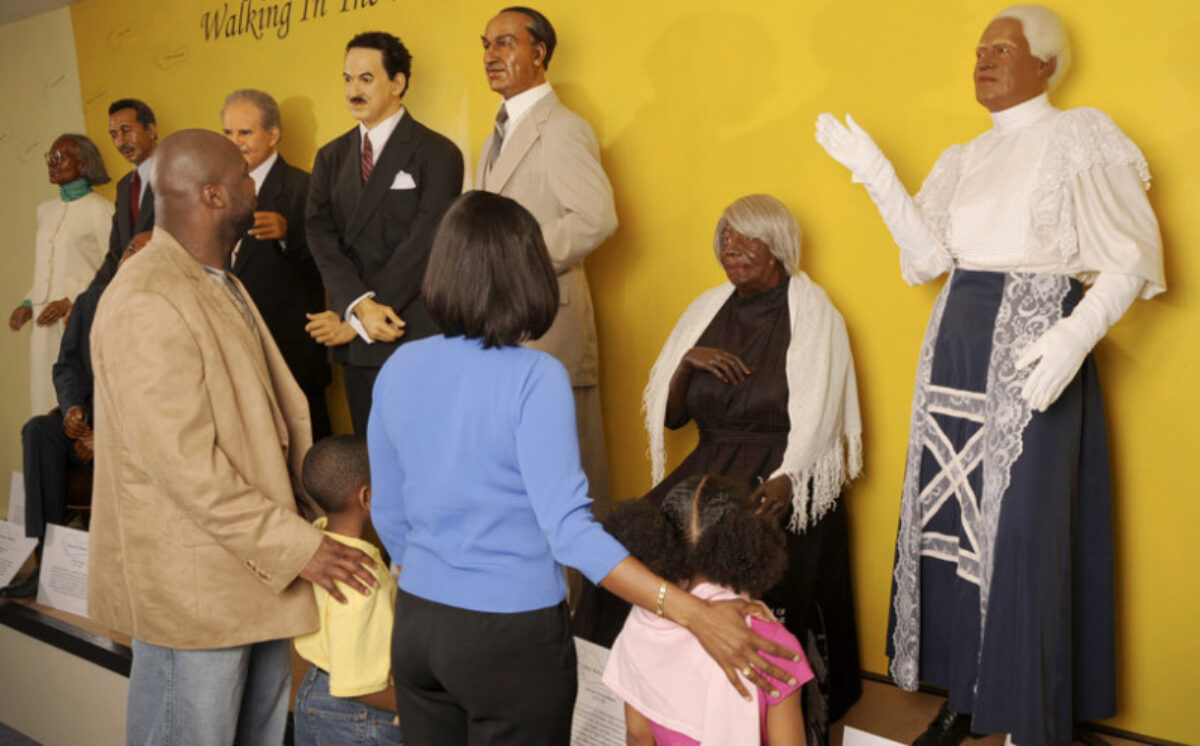 A child looks at wax figures with her mom