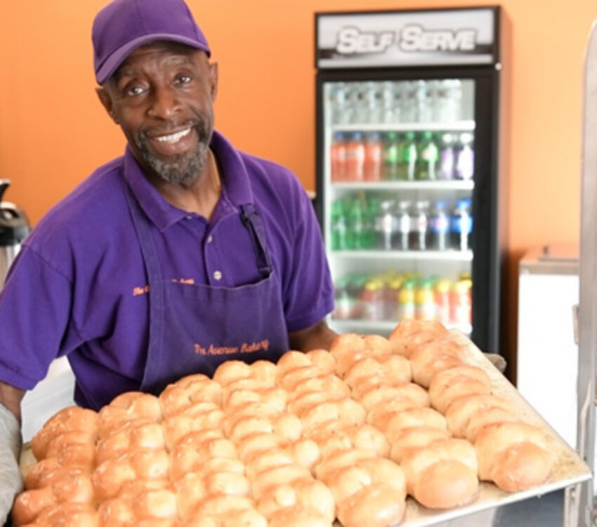 Baker holding up baked goods at the Avenue Bakery