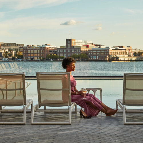 A woman enjoying a cocktail at the Pendry Hotel Pool in Fells Point.