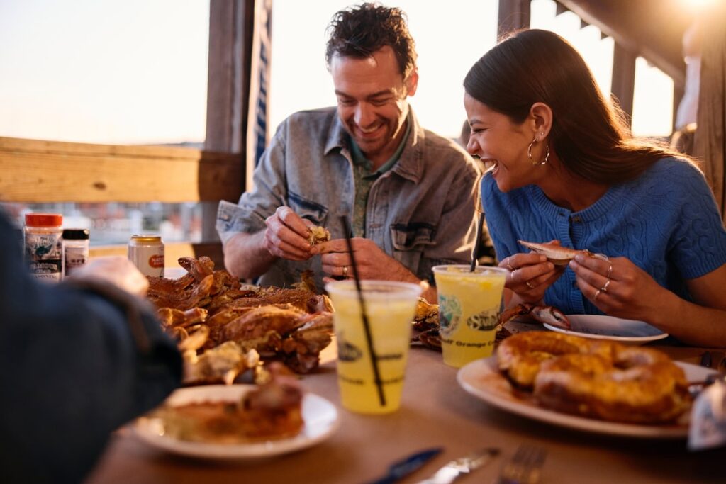 People laughing while cracking crabs and enjoying orange crushes
