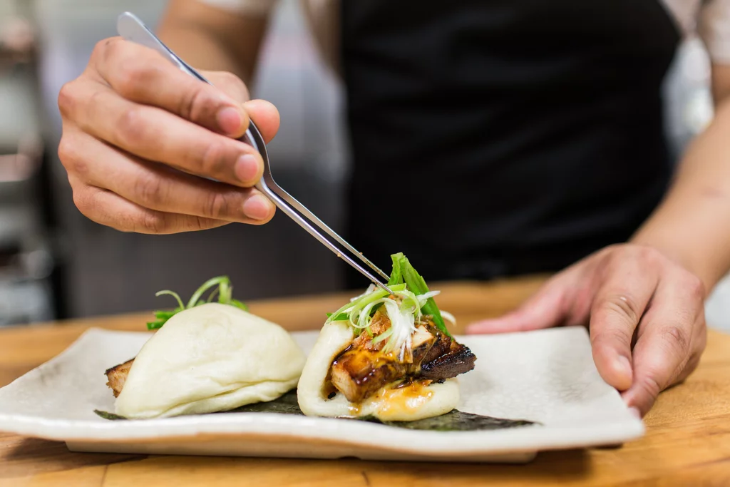 A chef puts the finishing touches on a pork bun at Dooby's