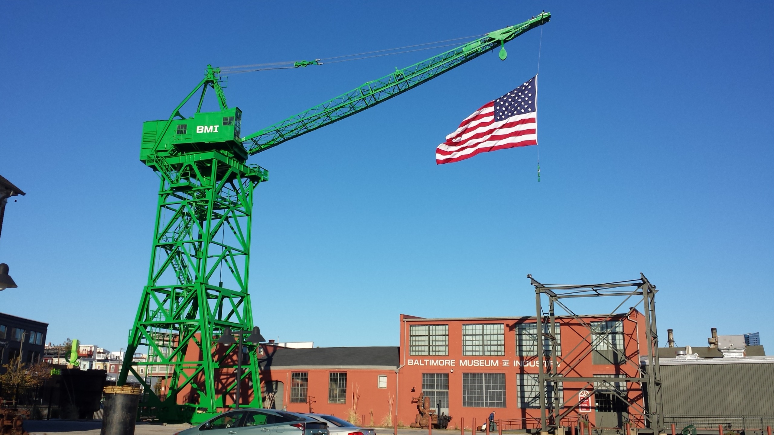 Green crane holding up an American flag outside the Museum of Industry.