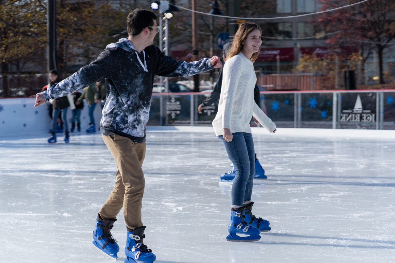 A man and woman ice skate outside