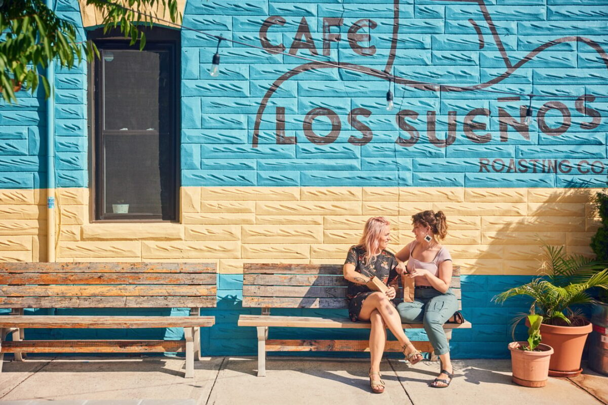 A female couple sits outside a coffee shop