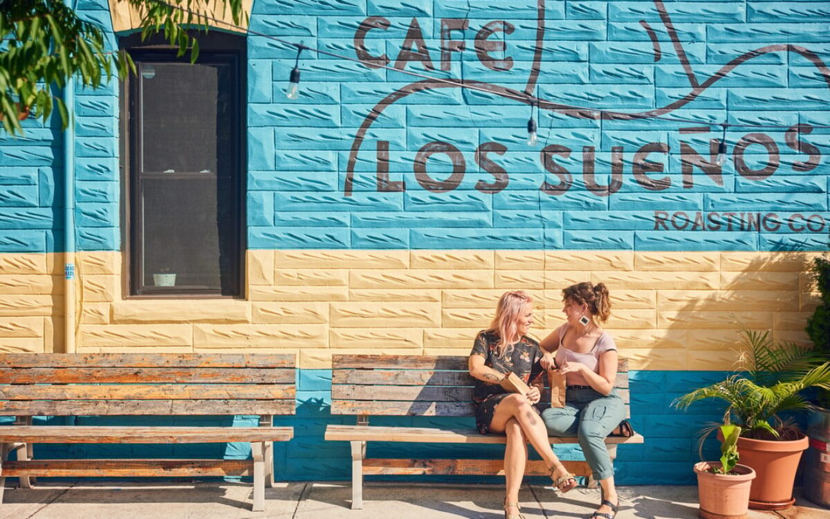 A female couple sits outside a coffee shop