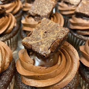 A chocolate cupcake with a chocolate ganache topped with a brownie from Codetta Cake Shop
