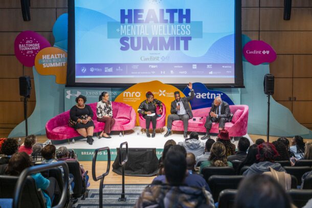 Panelists sitting on pink plush couches during a health summit