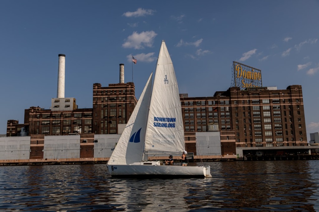 A sailboat in front of the Domino Sugar Factory