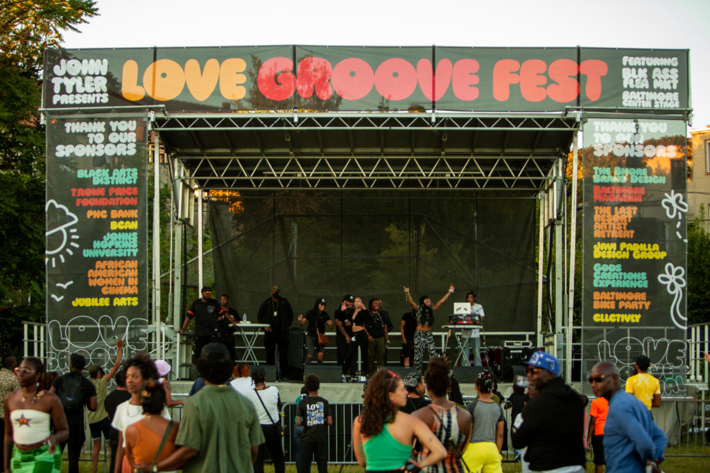 A crowd gathers in front of a colorful stage at Love Groove Festival