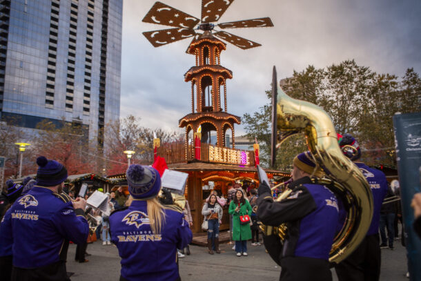 A marching band wearing Ravens gear surrounds a festive pyramid