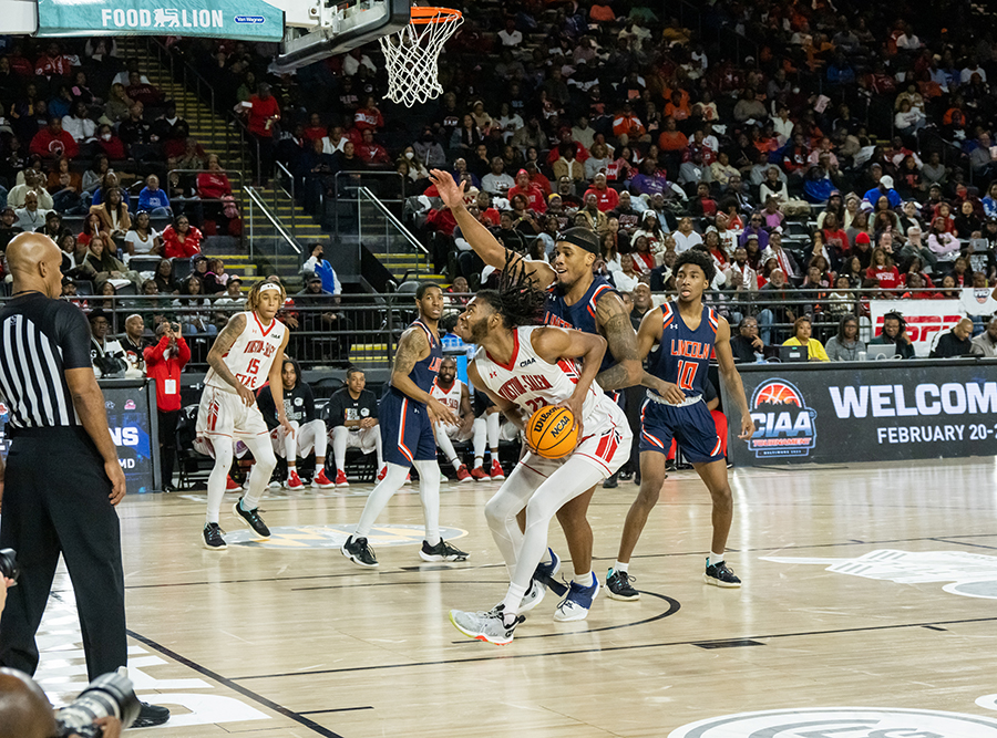 Two basketball players reach for a ball under the basket