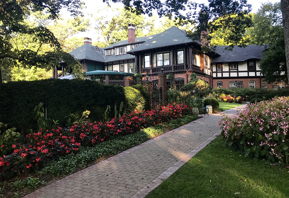 A walkway of pink roses leads to a quaint brick bed and breakfast