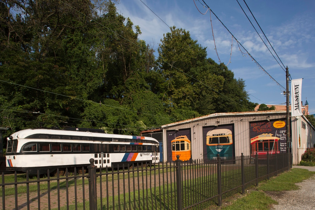 Four historic streetcars parked outside. 