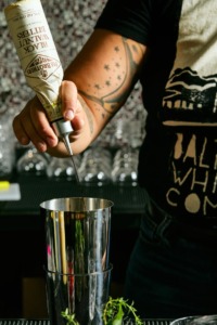 A bartender pours a beverage into a cocktail shaker