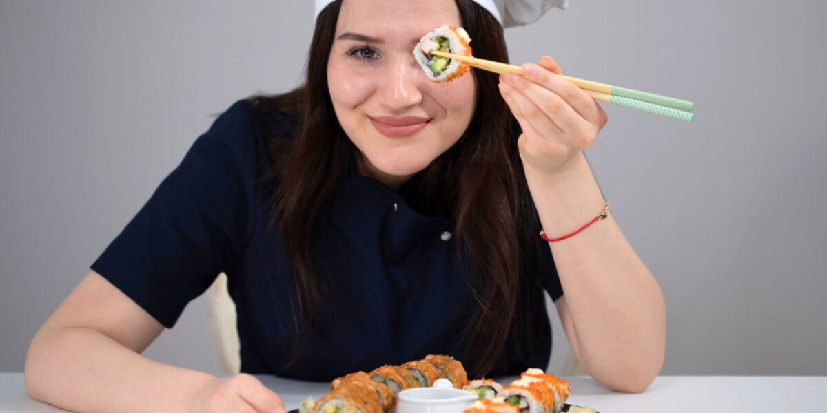 woman holding up sushi with chopsticks