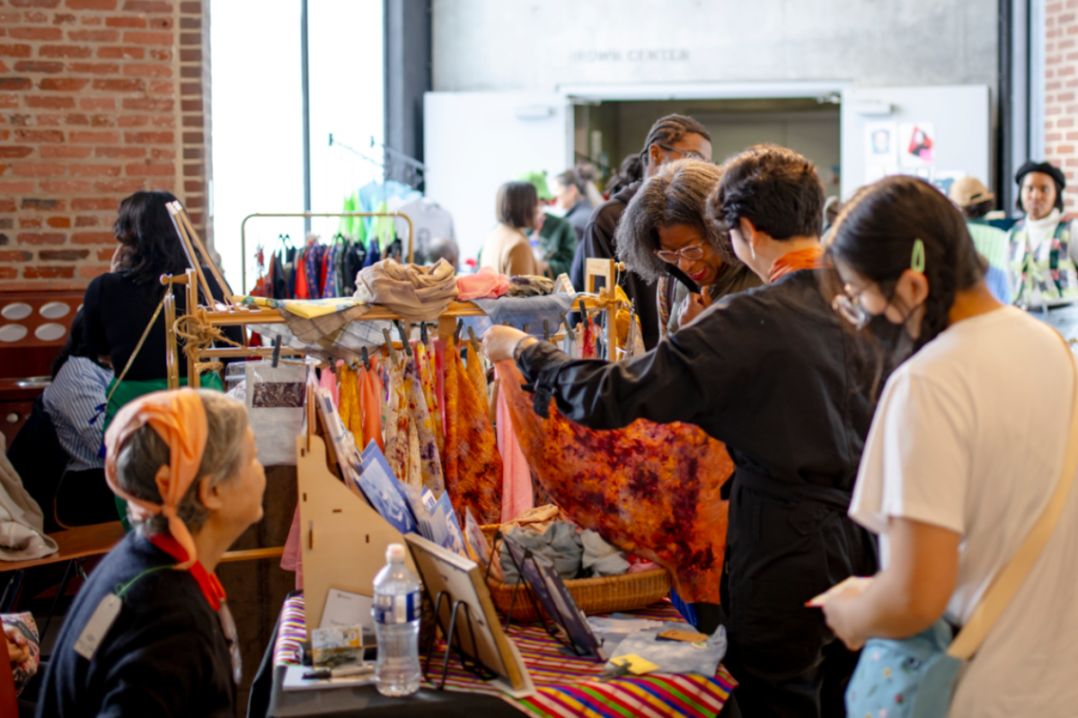 people at an art market looking at a scarf