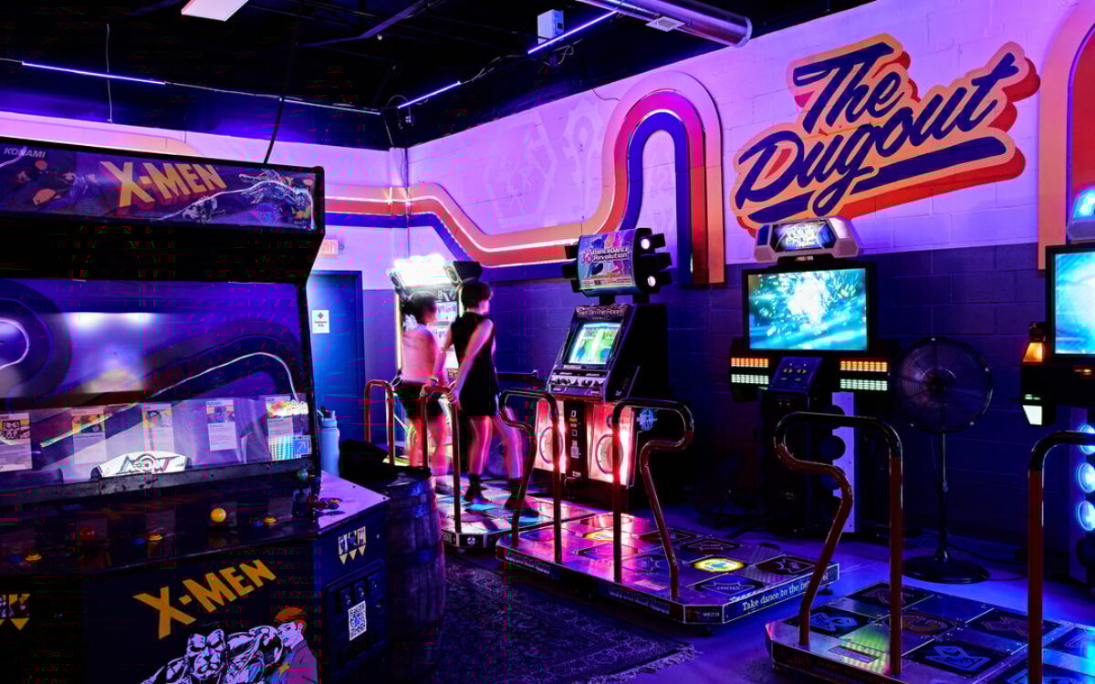 Two people play dance dance revolution in a dimly-lit room