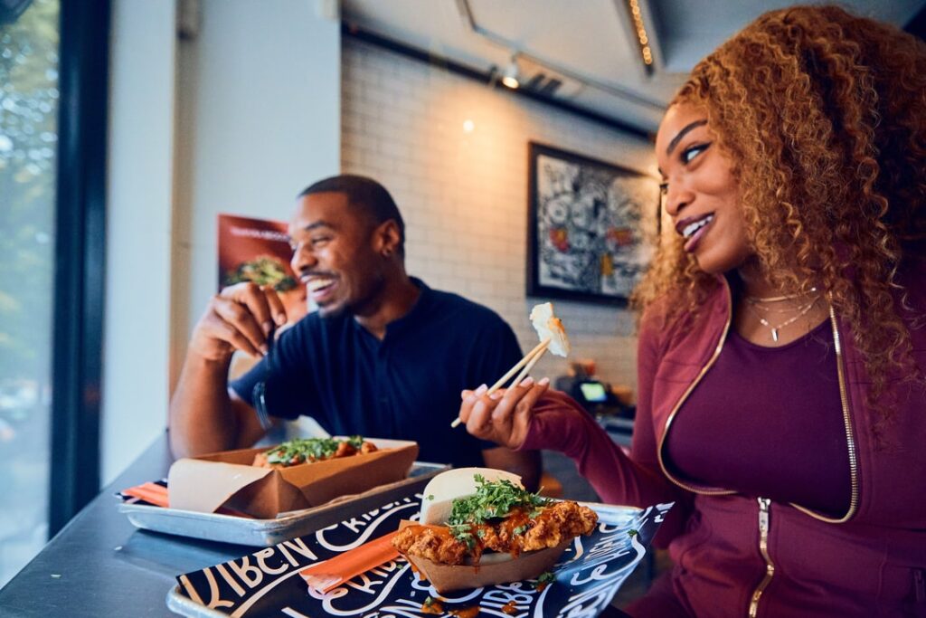 A black man and woman eat a counter at a fast-casual Asian restaurant