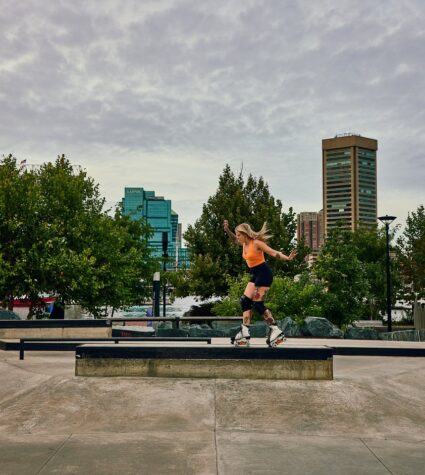 person skating at a skate park with the baltimore skyline in the background