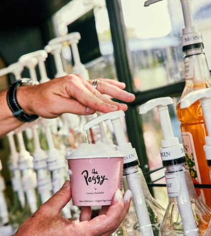 hand pushing syrup into a cup with ice to make a snowball