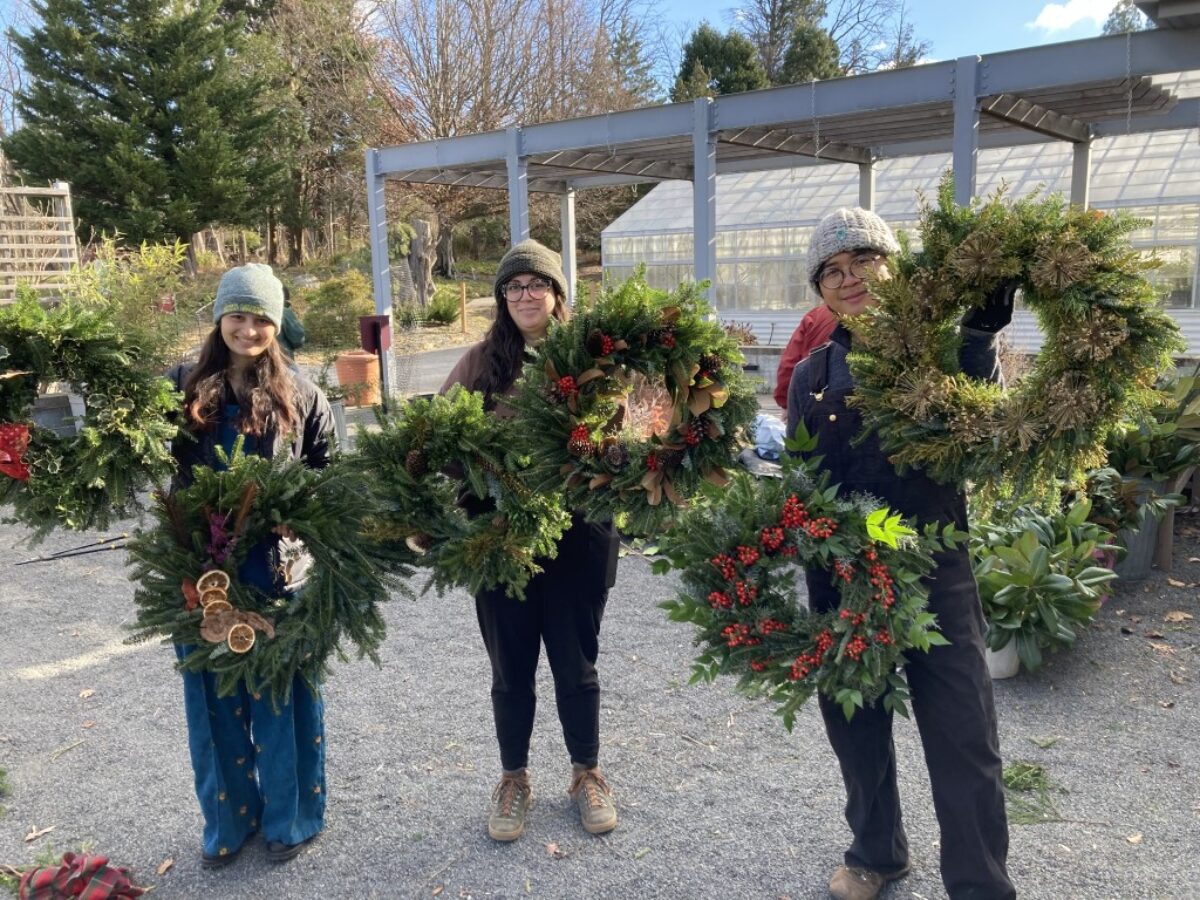 3 people holding wreaths
