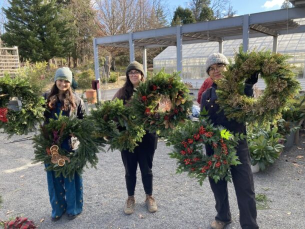 3 people holding wreaths