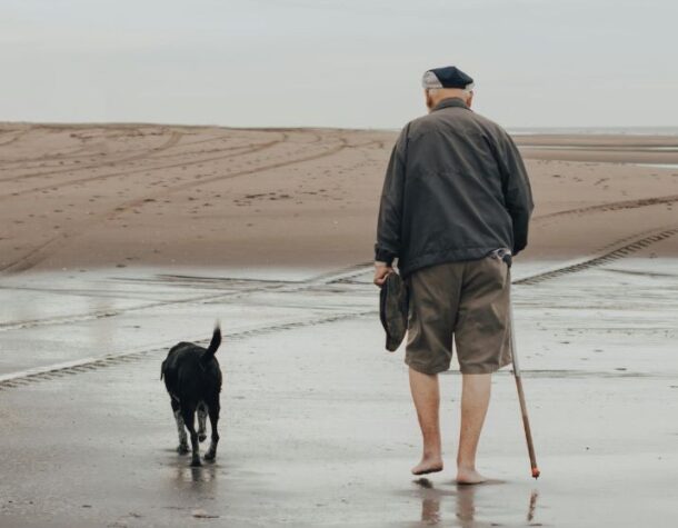 man and dog walking on beach
