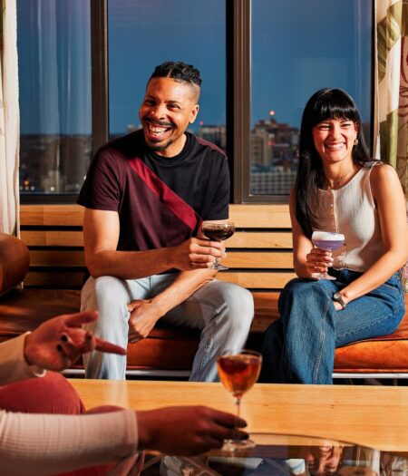 two people sitting on a bench with drinks in a restaurant