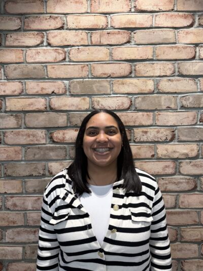 Apprentice Mya Mendoza poses in front of a brick wall