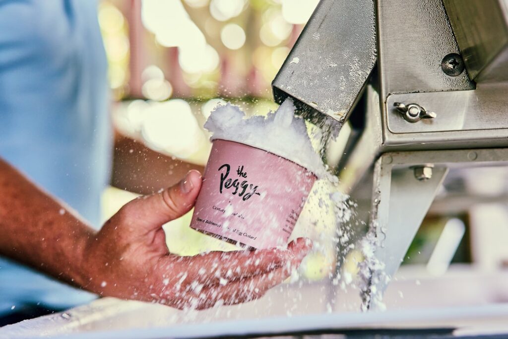 shaved ice entering a light pink cup from the peggy