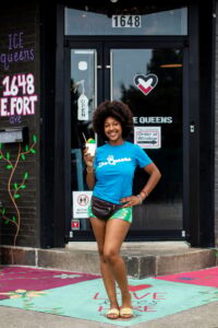 ice queens owner holds up a snowball in front of her store